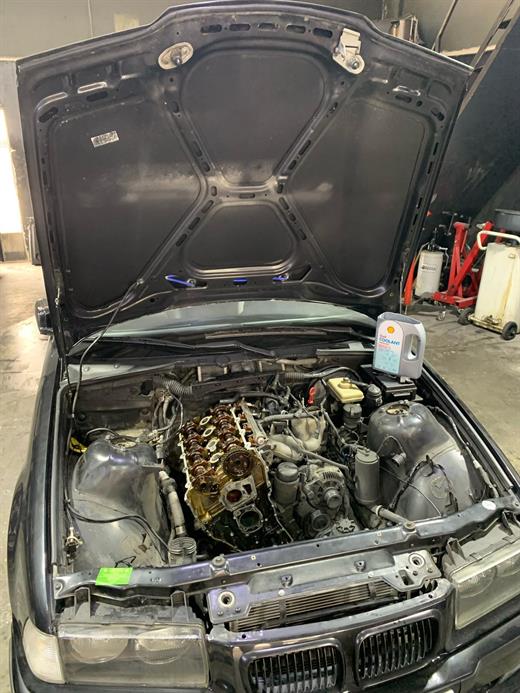 BMW E36 motor bölmesi açık, silindir kapağı sökülmüş eksantrik mili görünüyor