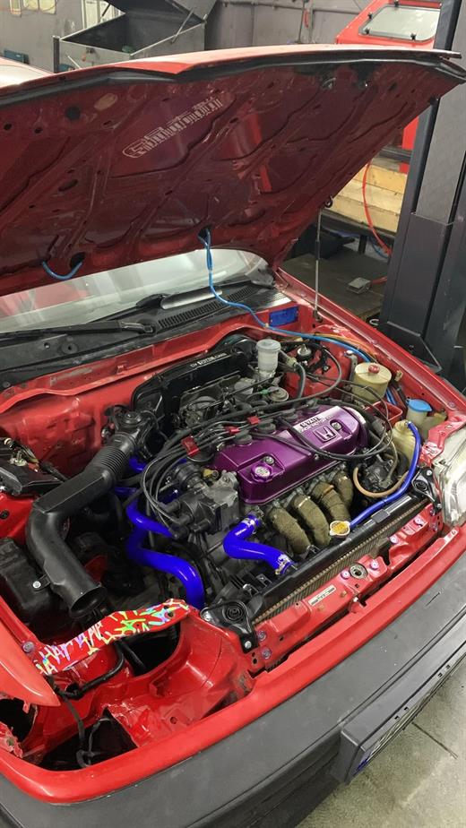 Kırmızı Honda Civic motor bölmesinde mor subap kapaklı D16 motor, mavi silikon hortumlar ve intercooler
